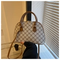 Dettaglio di borsa a conchiglia beige con motivo a trifoglio e tracolla in pelle marrone - caffè