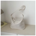 Detalle de bolso hobo minimalista en cuero beige con correa ancha sobre una mesa - Blanco