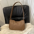 Bolso hobo vintage marrón con patrón floral geométrico negro sobre una silla de cuero - Marrón