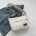 Minimalist white nylon messenger bag with adjustable wide strap shown on denim jacket - White