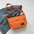 Minimalist orange crossbody bag with adjustable strap and designer patch on denim - Orange
