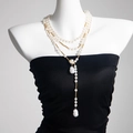 Macro detail of layered pearl necklace with star chain fringe and baroque pearl pendant - Gold