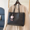 Bolso tote de cuero negro con correa y colgante de peluche rosa colgado de un perchero - Con Colgante / Negro