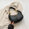Bolso de hombro negro media luna en cuero mate con hebilla dorada sobre blazer beige - Negro