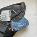 Hellblaue Jeans-Halbmond-Unterarmtasche mit silberner Kette auf grauem Blazer - Hellblau