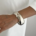 Detailaufnahme eines breiten, unregelmäßigen Wellenarmbands aus Silber im Liquid-Metal-Stil - Unregelmäßiger Flüssigmetall-Stil / Silber