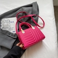 Magenta quilted crossbody bag with woven handle and gold hardware on grey suit - Rose Red