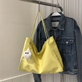 Gelbe Tragetasche mit Plüsch-Anhänger an Kleiderbügel vor Jeansjacke - Mit Anhänger / Gelb