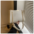 Detail view of white croc-embossed leather texture and gold chain link strap on the handbag - White