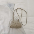 Détail du sac froissé beige avec fine bandoulière sur une texture de tissu blanc - Blanc Cassé