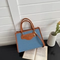 Dettaglio della borsa tote color-block con corpo in denim blu, finiture in pelle e zip metallica - Azzurro