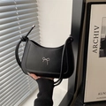 Schicke schwarze Hobo-Tasche mit silberner Schleife in modischer Lifestyle-Umgebung - Schwarz