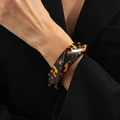 Close-up of a wide resin leopard print bangle against a professional black suit sleeve - Tortoiseshell Yellow Black