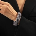 Macro shot of wide zebra print resin bangle paired with a black blazer for high fashion style - Zebra Black White