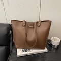 Chic brown faux leather tote bag with gold metal buckle on a black textured table - Brown