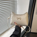 Chic cream white faux leather shoulder bag with a gold bow accent and adjustable strap - White