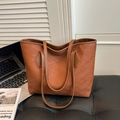 Large brown textured tote bag for women placed next to a laptop on a dark sofa - Brown