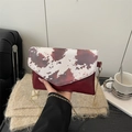 Détail du petit sac bandoulière en similicuir avec rabat imprimé vache et chaîne dorée - Rouge