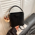 Chic black bucket handbag with top handle and cute plush bear charm on white books - With Pendant / Black