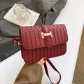Elegant wine red woven crossbody bag with gold buckle on a stylish suit backdrop - Red