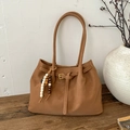 Detalle de bolso tote de cuero marrón con colgante de cuentas sobre superficie de madera - Con Colgante / Marrón