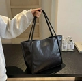 Dettaglio di una borsa tote vintage nera in pelle lucida con spalline sottili e capiente - Nero