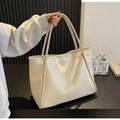 Dettaglio della borsa tote crema che mostra la trama della pelle morbida e i manici fini - Bianco Sporco