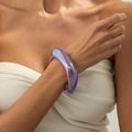 Dettaglio di un bracciale rigido in resina viola iridescente con finitura perlata al polso - AB Viola (03031)