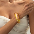 Dettaglio del bracciale rigido in resina iridescente con riflessi aurora indossato dal modello - AB Giallo (03031)