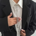 Detail of silver tassel brooch with metal bead chains on a black suit blazer - Silver