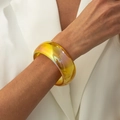 Dettaglio di un ampio bracciale rigido in resina gialla trasparente con riflessi cangianti - AB Giallo (03032)