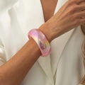 Vista dettagliata del bracciale in resina rosa cangiante indossato su blazer bianco - AB Rosa