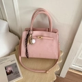 Sac seau rose texturé avec fermoir doré et pendentif de baseball dans un décor chaleureux - Avec Pendentif / Rose