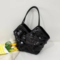 Gros plan d'un sac à paillettes noires avec texture scintillante et doubles anses fines - Noir