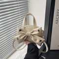 Cream crossbody bag with bow and star rivets shown from a side view by model - White