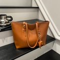 Large brown leather tote bag with elephant charm on black wooden steps for office - Brown