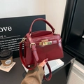Fashionable burgundy leather handbag with golden twist lock for versatile crossbody wear - Red