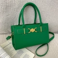 Borsa a tracolla verde chic con chiusura a cuore dorata e texture in pelle sul divano - Verde