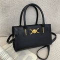 Classic black leather handbag with gold heart buckle and crossbody strap on white fabric - Black
