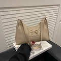Detail of a chic beige patent leather underarm bag with a golden metal bow accessory - Khaki