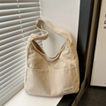 Detalle del bolso tote de pana blanca con tela texturizada y etiqueta de moda - Caqui