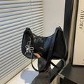Minimalist black hobo shoulder bag with silver bow charm and glossy leather finish - Black