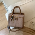 Detail of retro textured brown leather and herringbone weave crossbody bag on a white sofa - With Pendant / Brown