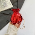 Metallic red candy-shaped evening bag with a gold chain strap held by hand - Red