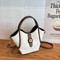 Elegante bolso de cubo crema con asas marrones y cierre dorado sobre mesa de madera - Blanco