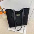 Elegante bolso tote de pana negra con correas de cuero y etiqueta de marca en fondo acogedor - Negro