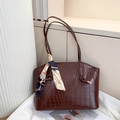 Close-up of crocodile pattern leather tote bag with elegant blue printed silk scarf detail - Brown
