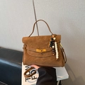 Detail of a brown matte handbag featuring a wooden bead charm and golden twist lock - With Pendant / Brown