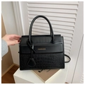 Elegant black handbag with crocodile texture and golden lettering on a modern pedestal - Black