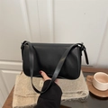Bolso bandolera minimalista de cuero negro con solapa mostrado en un ambiente acogedor - Negro